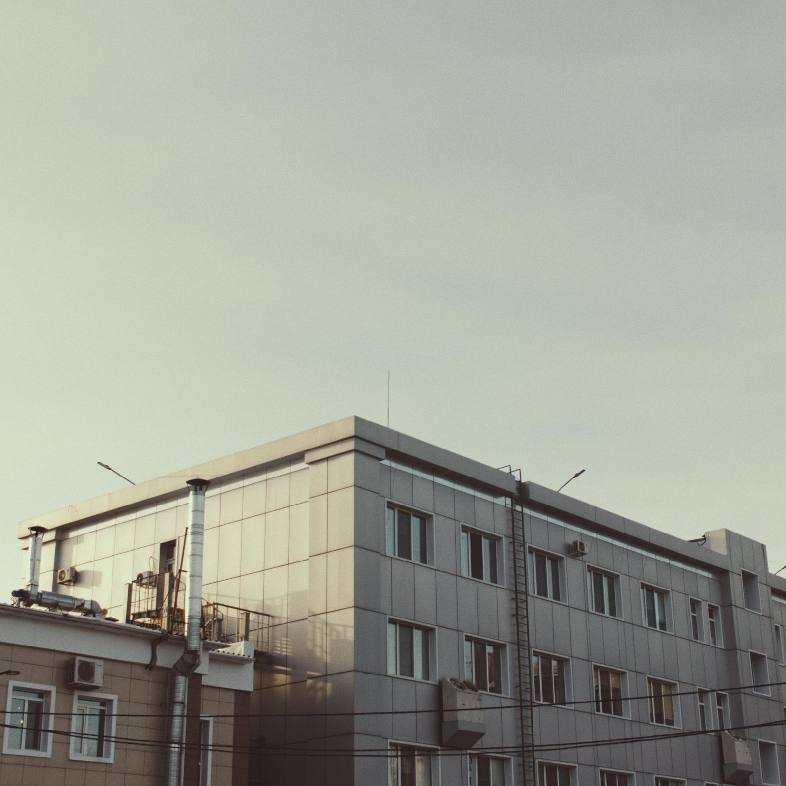A contemporary office building under a clear sky with warm lighting.